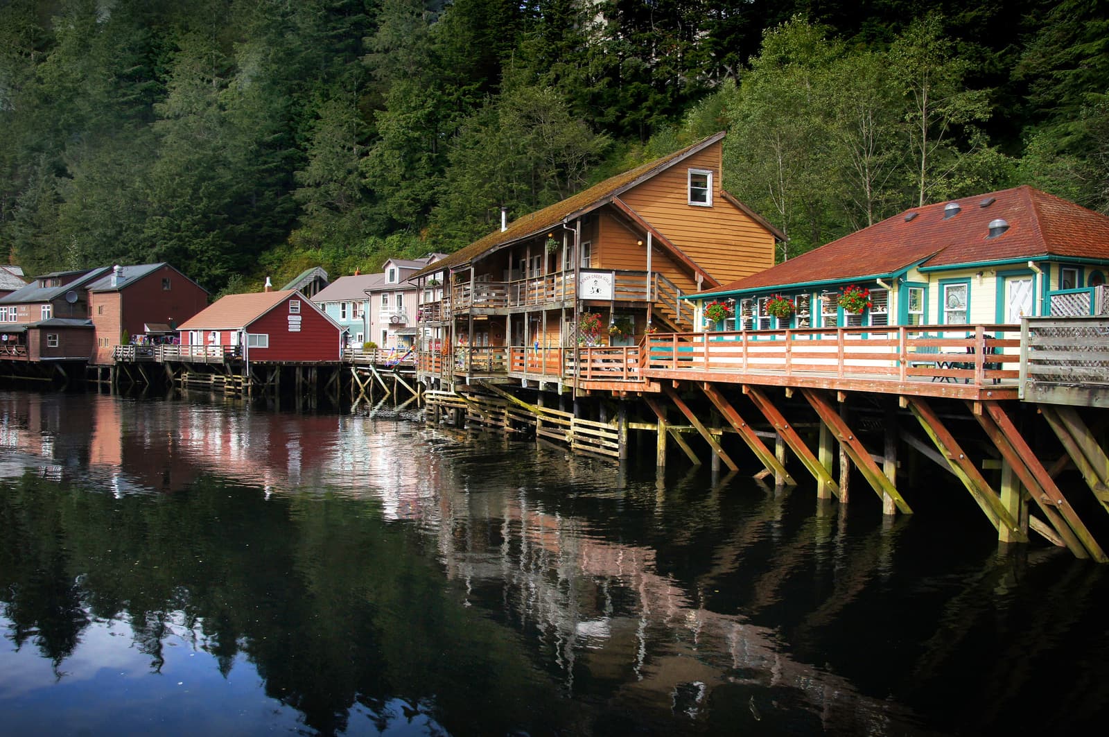 Wooden houses on pilings along the Creek Street boardwalk, reflected in Ketchikan Creek