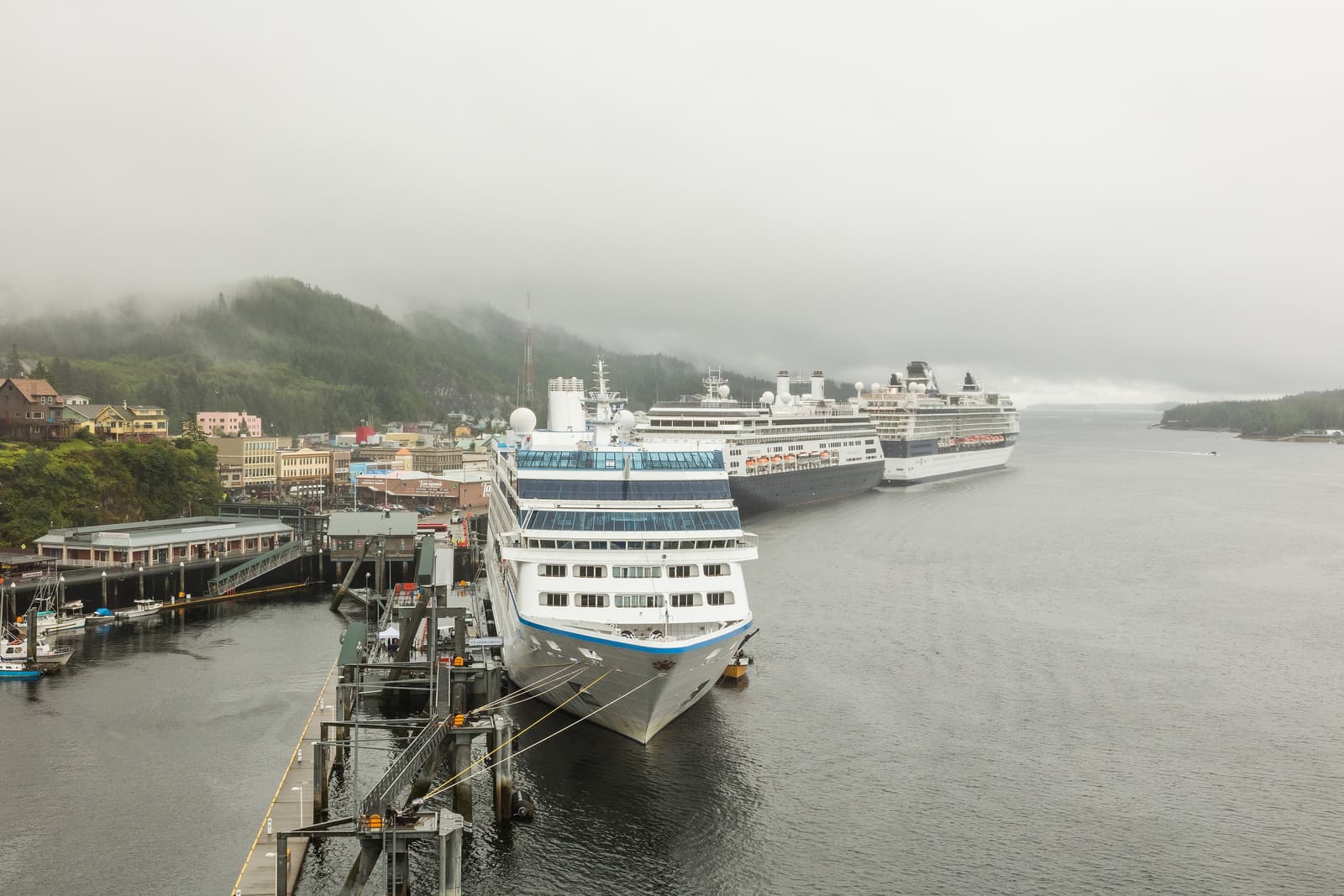 Cruise ships docked along the downtown Ketchikan waterfront under low cloud