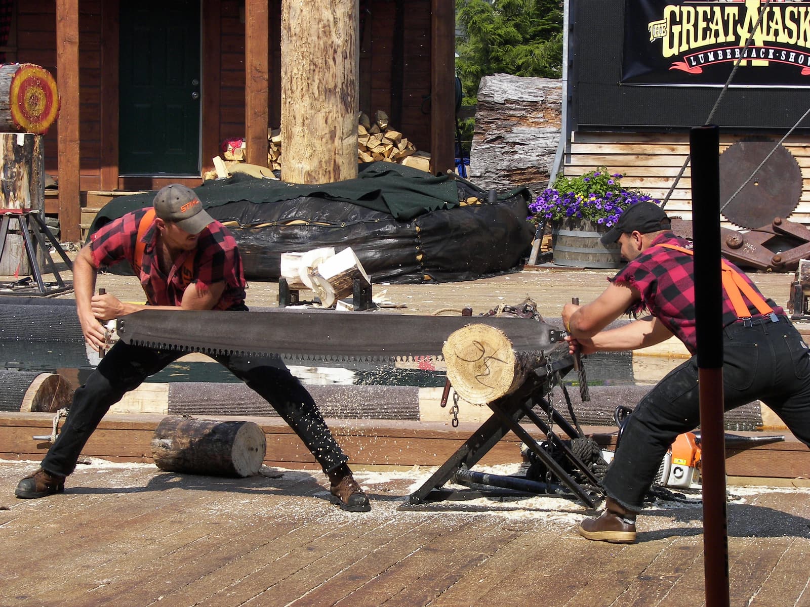 Two lumberjacks competing in a crosscut saw event at the Great Alaskan Lumberjack Show