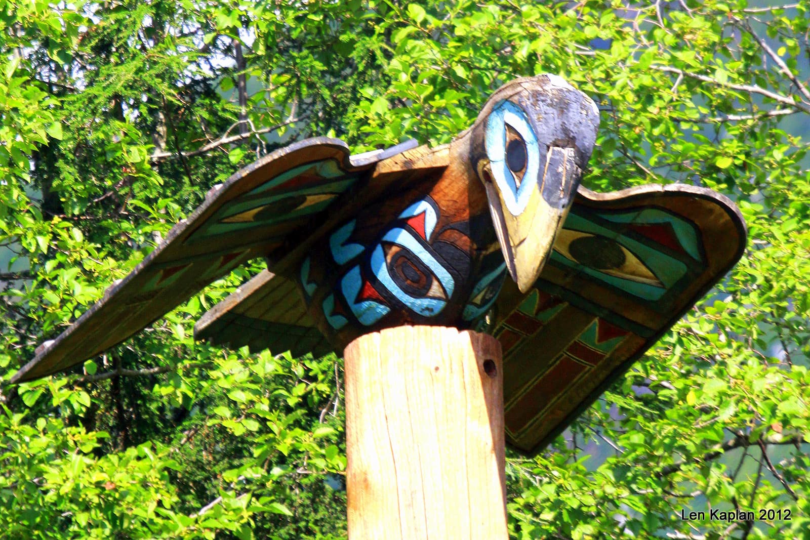 A carved bird figure on top of a totem pole at Totem Bight, beside Potlatch Park